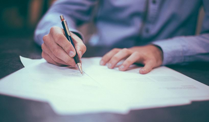 A person's hands signing papers