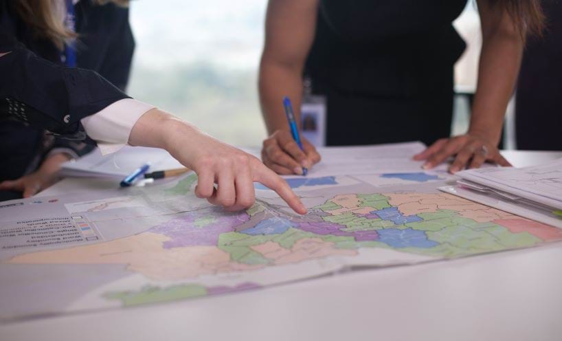 Two people pointing to a map of Victoria with coloured sections showing council areas