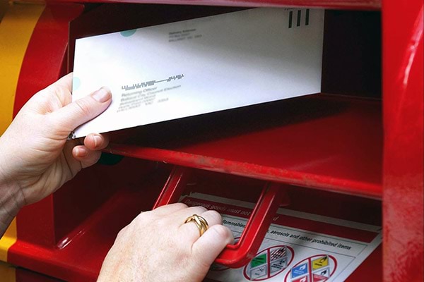 Woman's hand putting envelope through the letter box